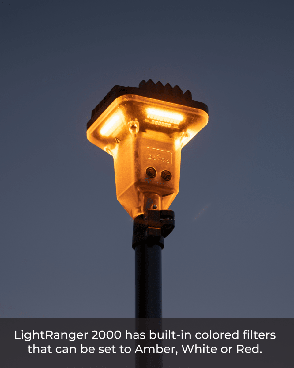 The LightRanger 2000 is shown illuminated against a twilight sky, highlighting its built-in colored filters that can be set to amber, white, or red.